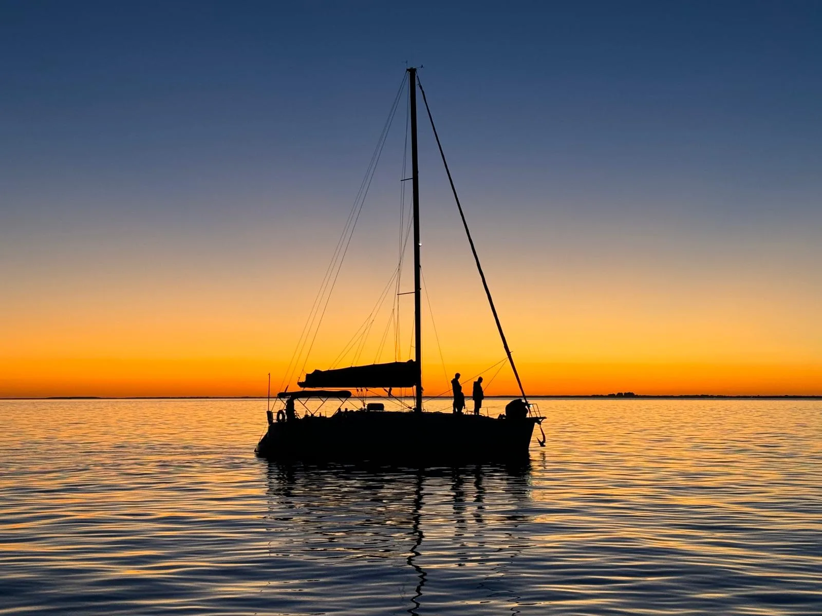 Friends aboard a sailboat at sunset